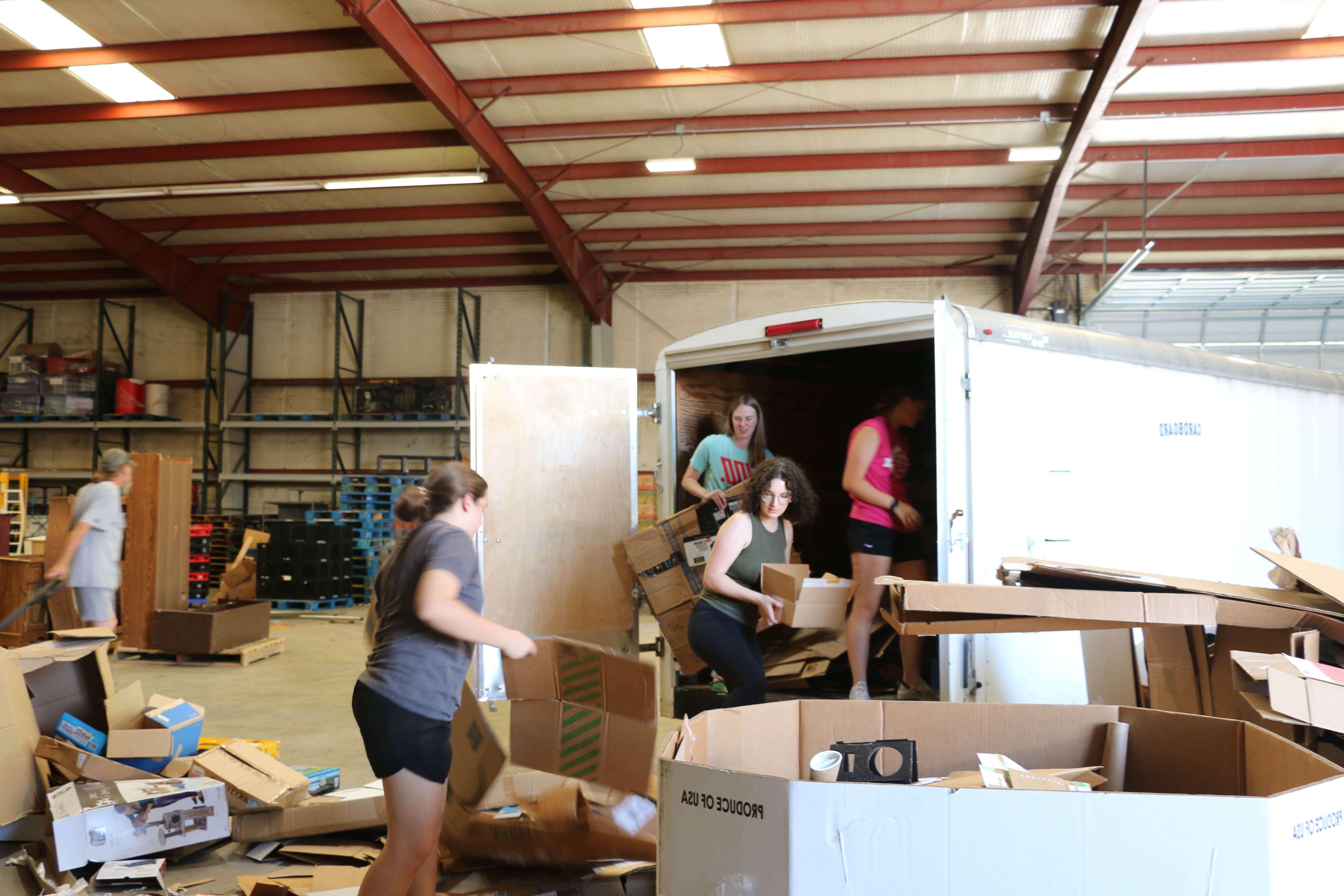 学生在部仓库服务，从拖车上卸下纸板回收