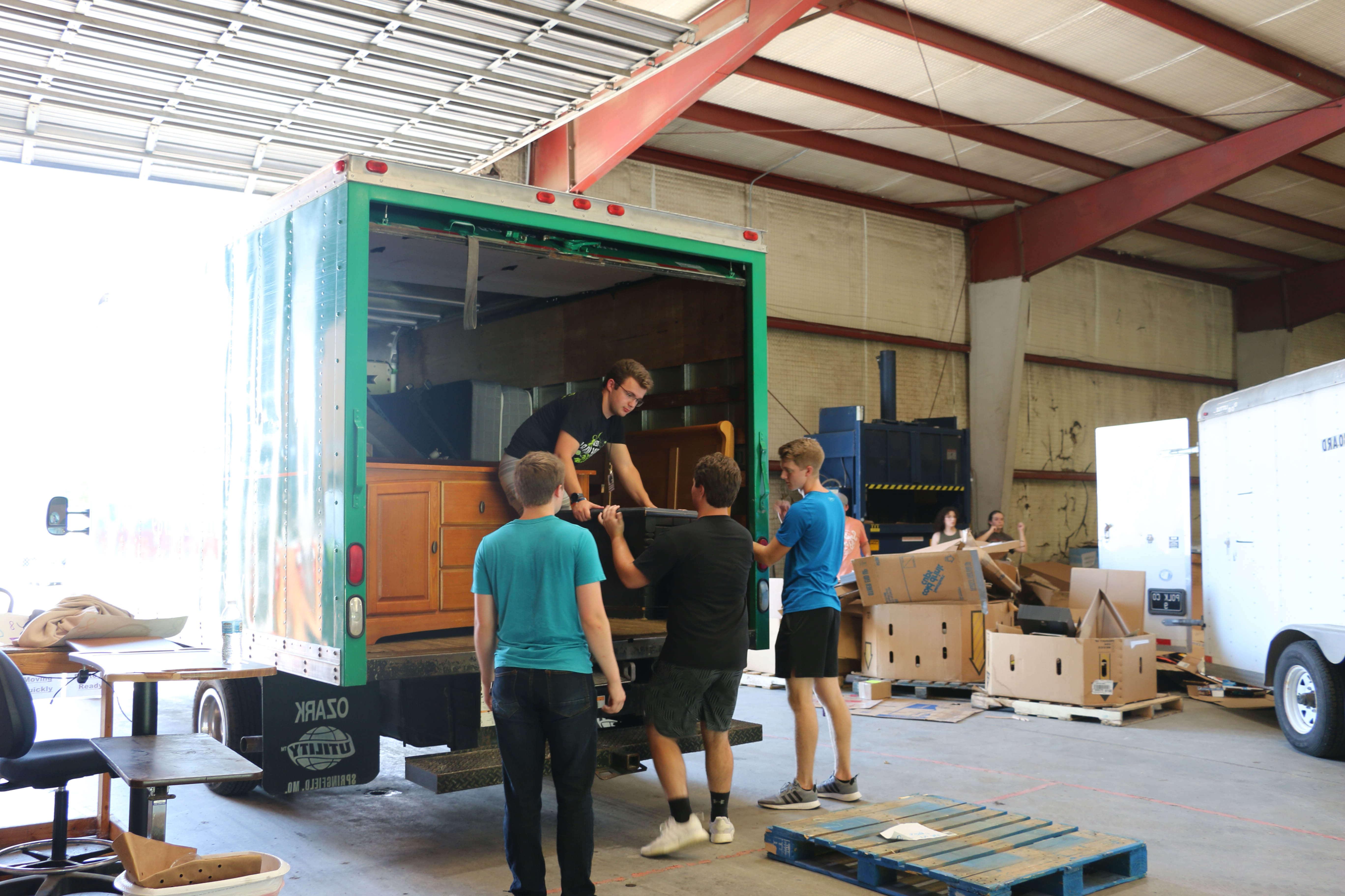 学生们在仓库里卸下捐赠的家具拖车